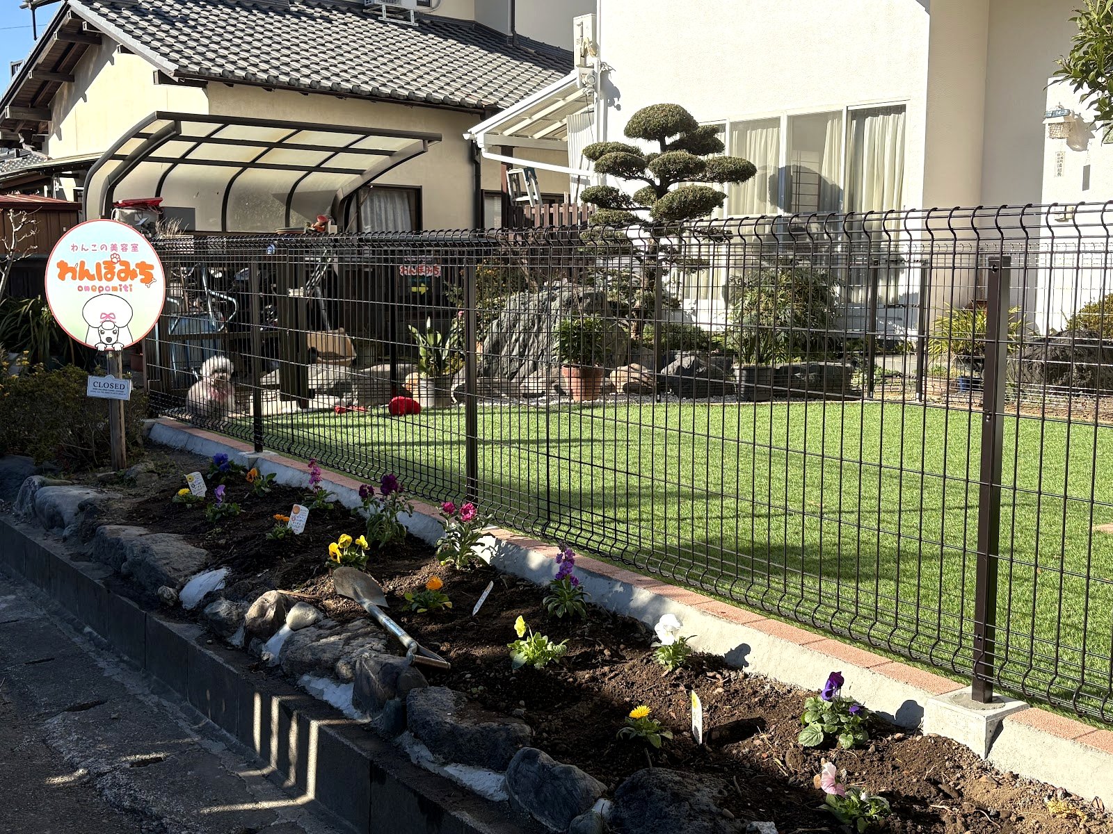わんぽみちの入り口。手描きの丸看板と、庭さきの花壇